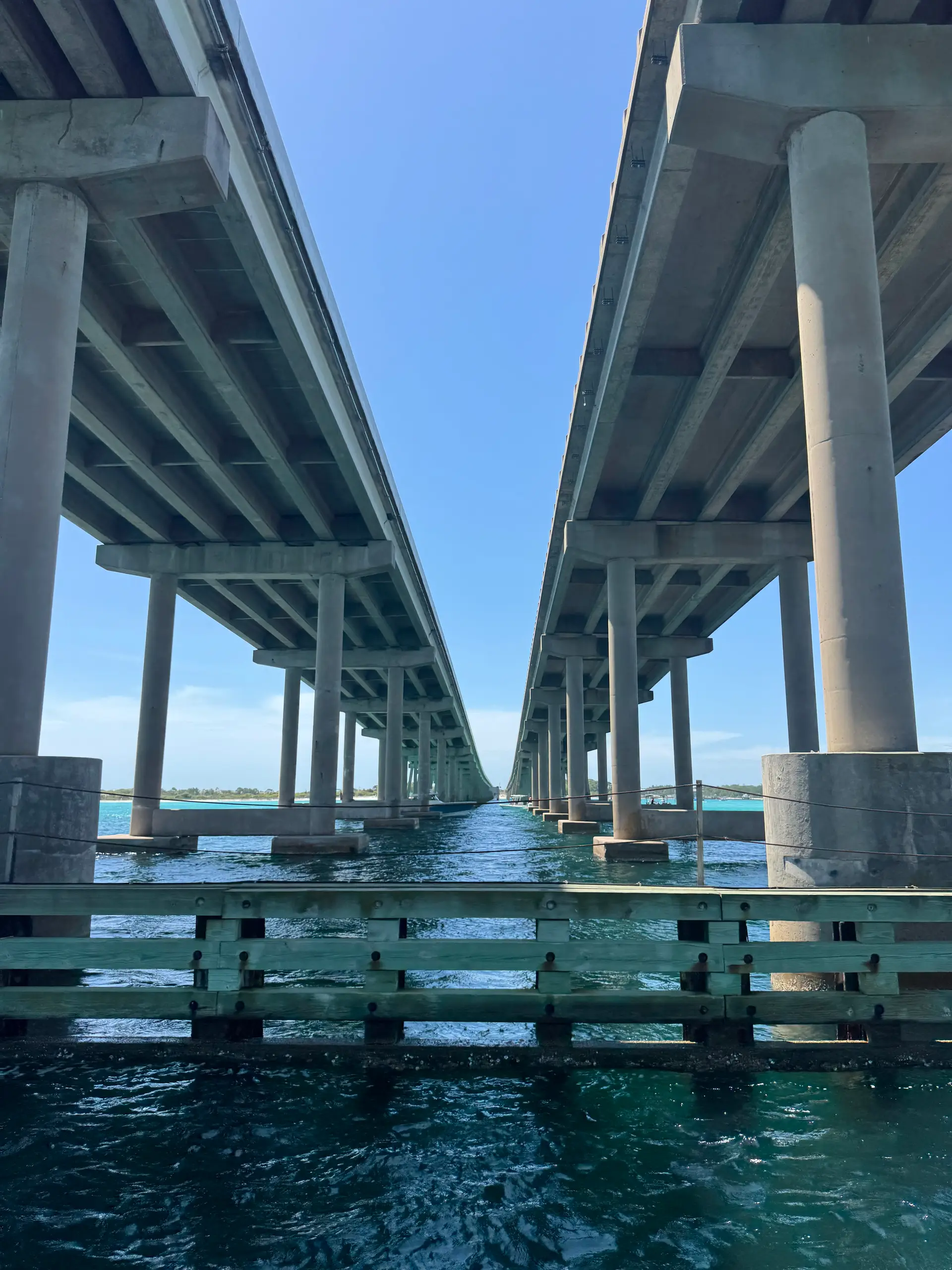 Twin elevated highway bridges on concrete piers receding over turquoise water.