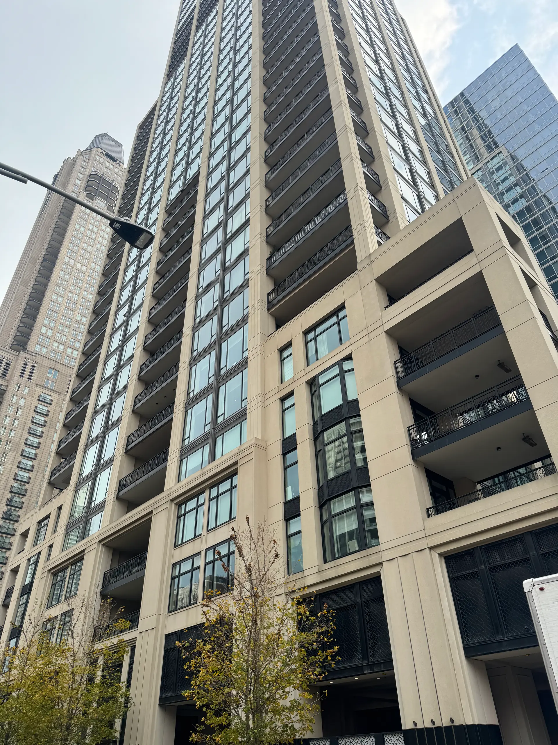 Looking up the facade of a completed residential tower with rows of balconies against the sky.
